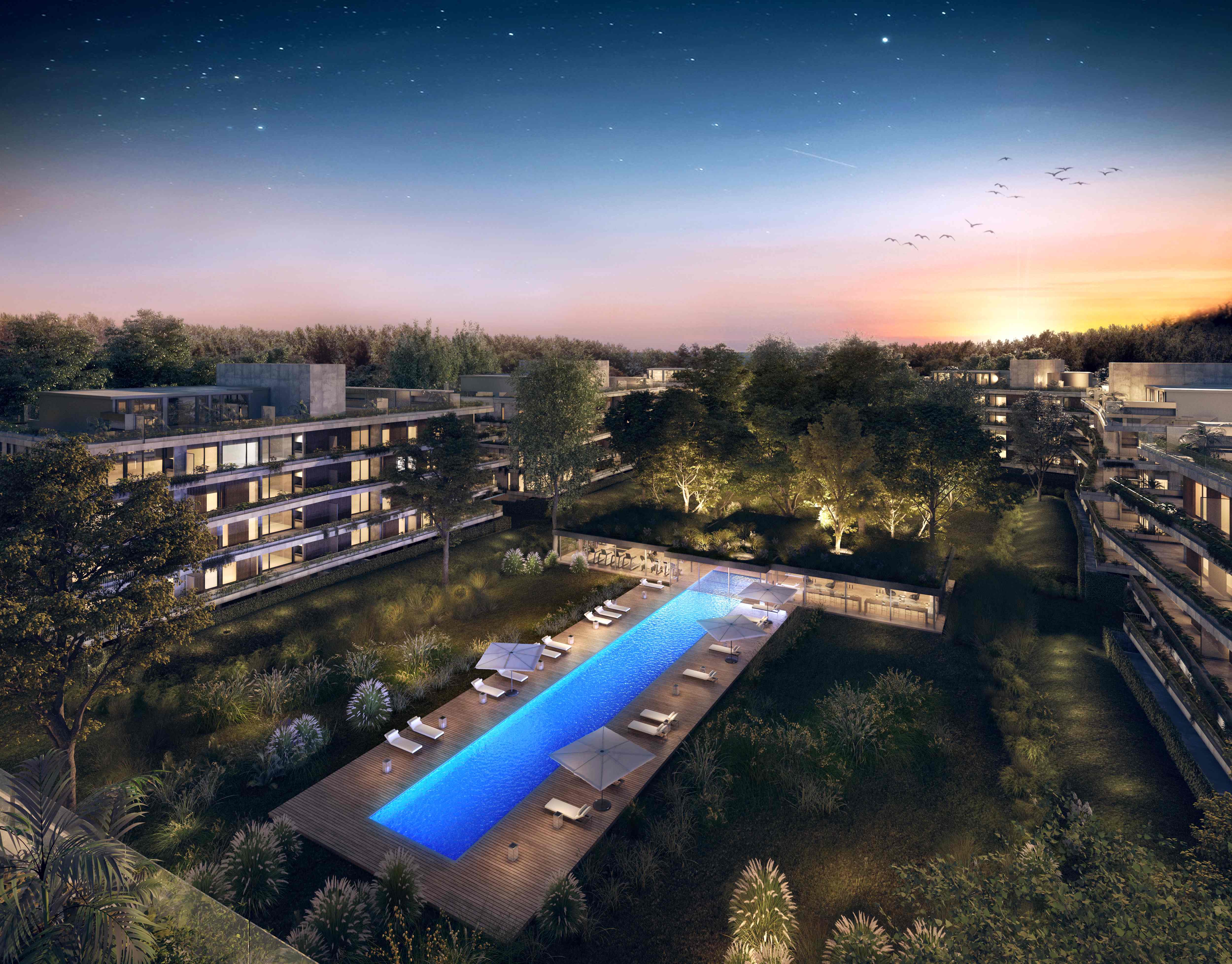 Vista aerea panoramica del complejo Bosque Tortugas al atardecer con modulos residenciales, piscina central y bosque nativo