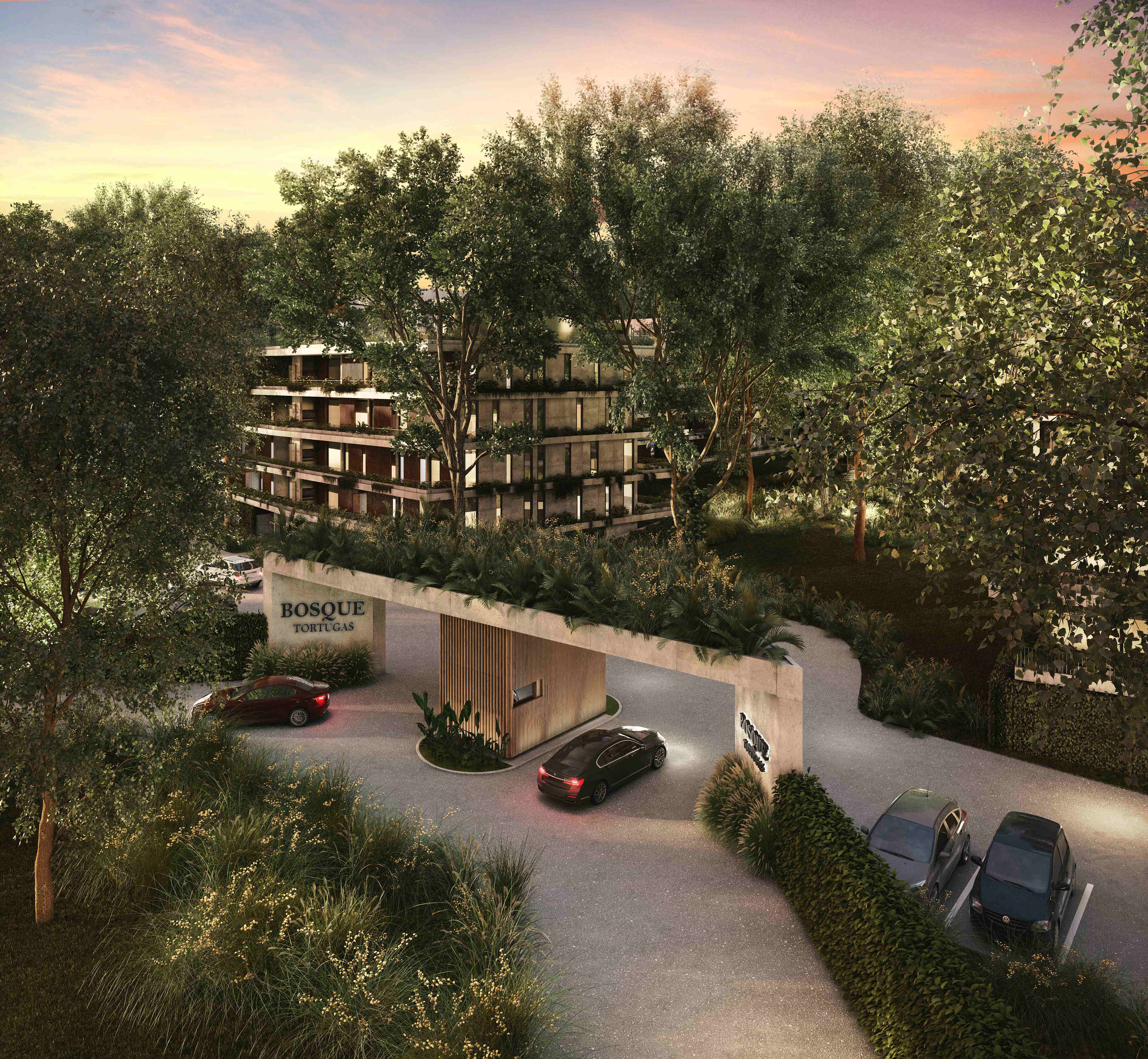 Vista aerea del acceso a Bosque Tortugas al atardecer con garita de madera, vehiculos y modulos residenciales entre bosque nativo